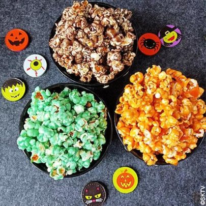 Vus du dessus, 3 bols de popcorn coloré et pastilles de chocolat sur le thème d'halloween.